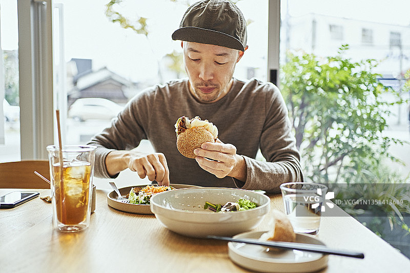 亚洲男子在素食咖啡馆吃素食汉堡图片素材
