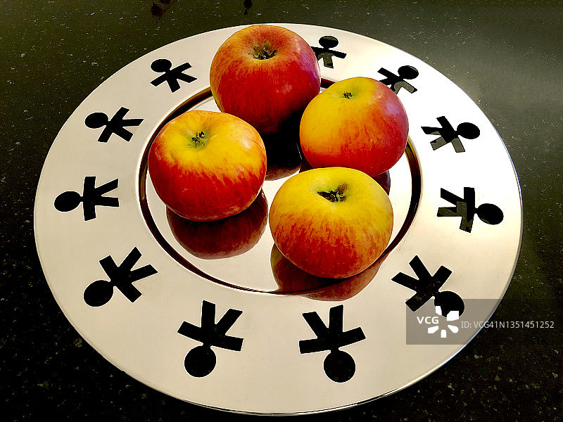 银色盘子里四个苹果的特写图片素材