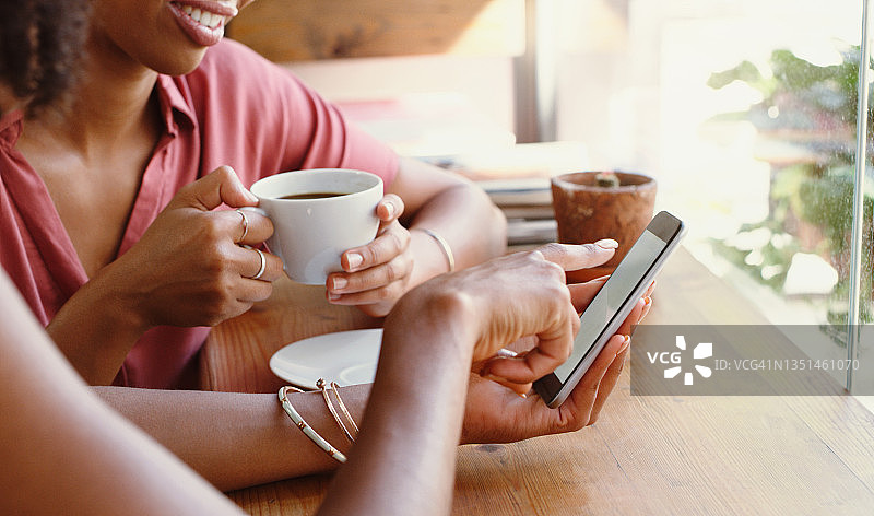 两位朋友在咖啡馆一起使用手机的照片图片素材