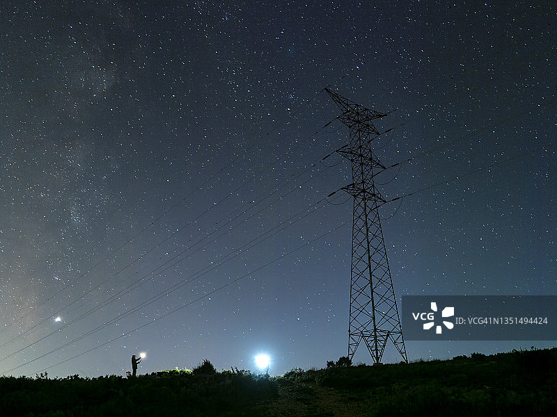 电工在夜间山区维修高压电塔图片素材