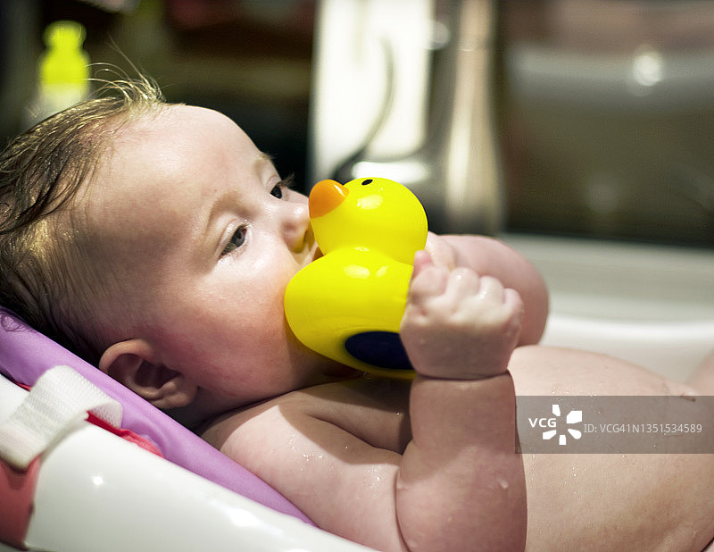 洗澡时拿着小黄鸭的婴儿图片素材