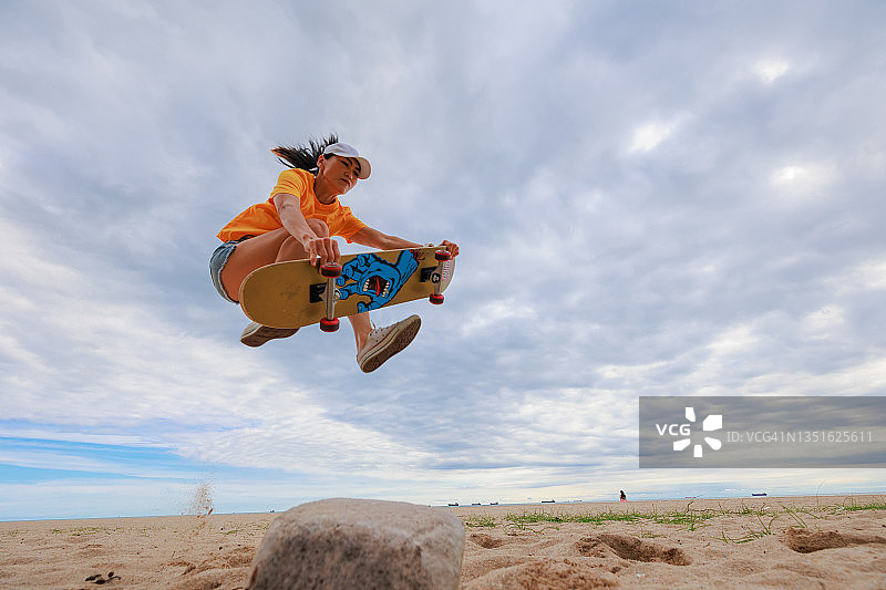 亚洲女人在海滩上玩滑板图片素材