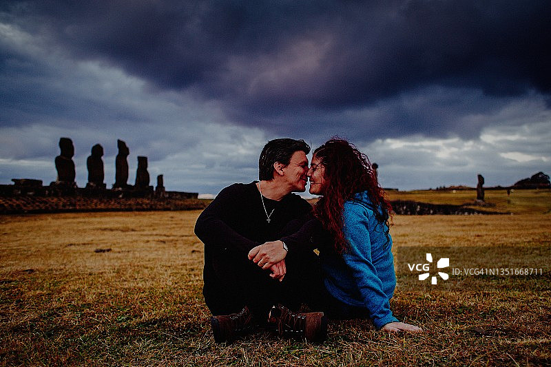 情侣在复活节岛欣赏日落，背景是摩艾石像图片素材