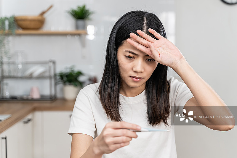用体温计测量体温的年轻亚洲女性图片素材