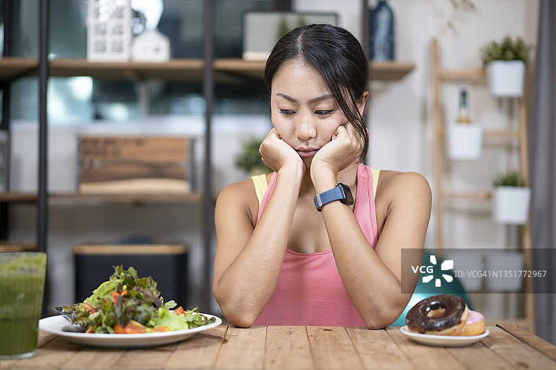 苗条的女孩在垃圾食品和健康蔬菜之间犹豫，节食图片素材