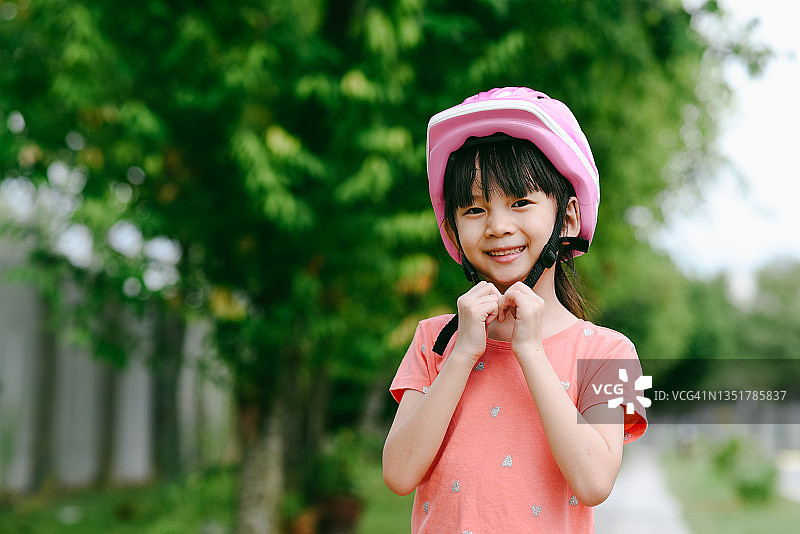 快乐的可爱亚洲女孩戴上自行车头盔图片素材