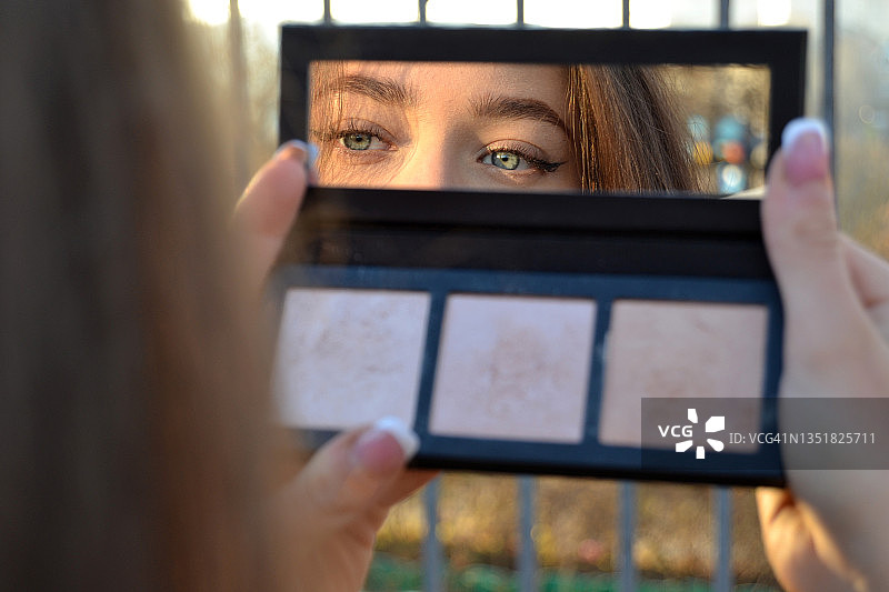 一个年轻女人在化妆镜中的折射。图片素材