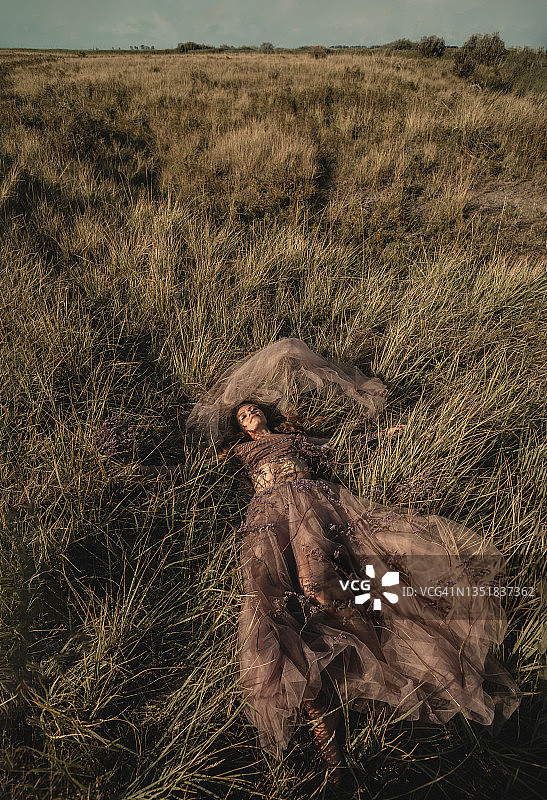 年轻漂亮的女孩梦想躺在神奇的草地上图片素材