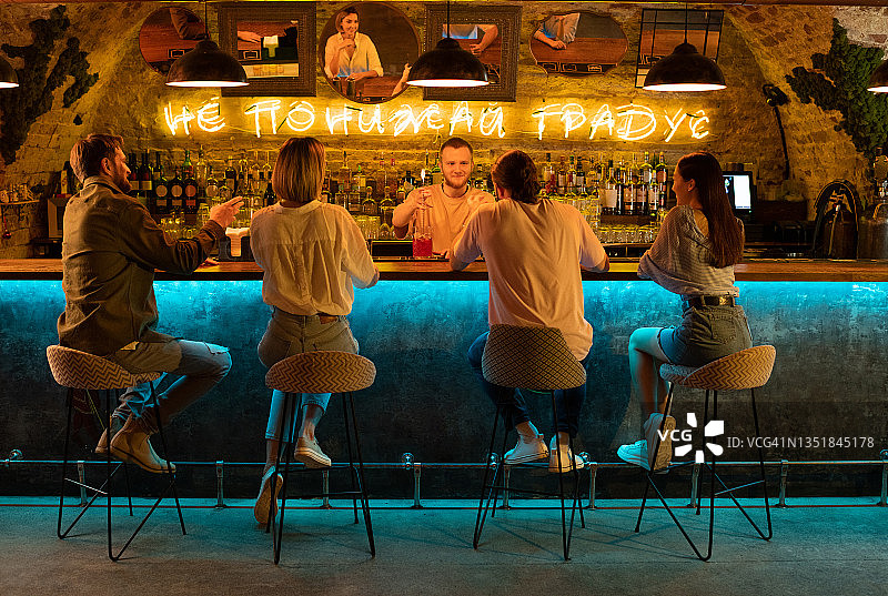 朋友们在酒吧与调酒师交谈图片素材