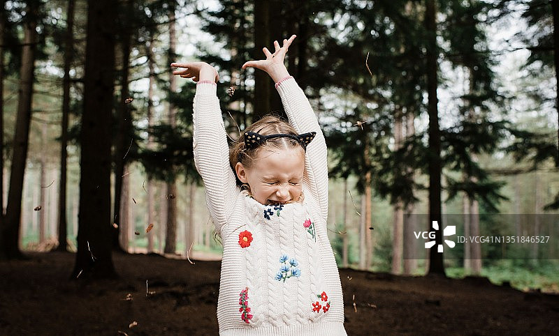 在森林里向上抛树叶和树枝的女孩图片素材