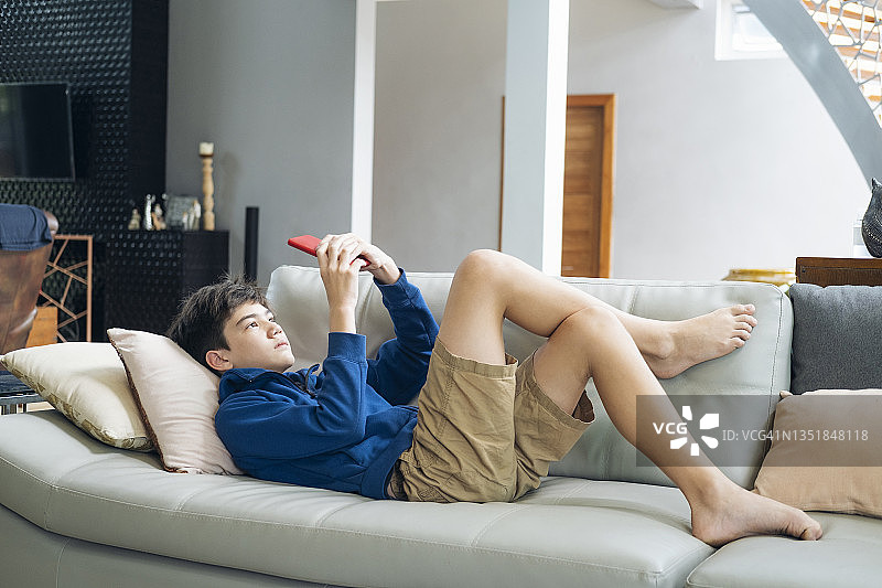 男孩在家用手机玩网络游戏图片素材