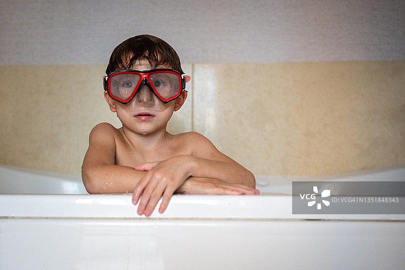 戴着潜水面罩靠在浴缸边缘的男孩图片素材