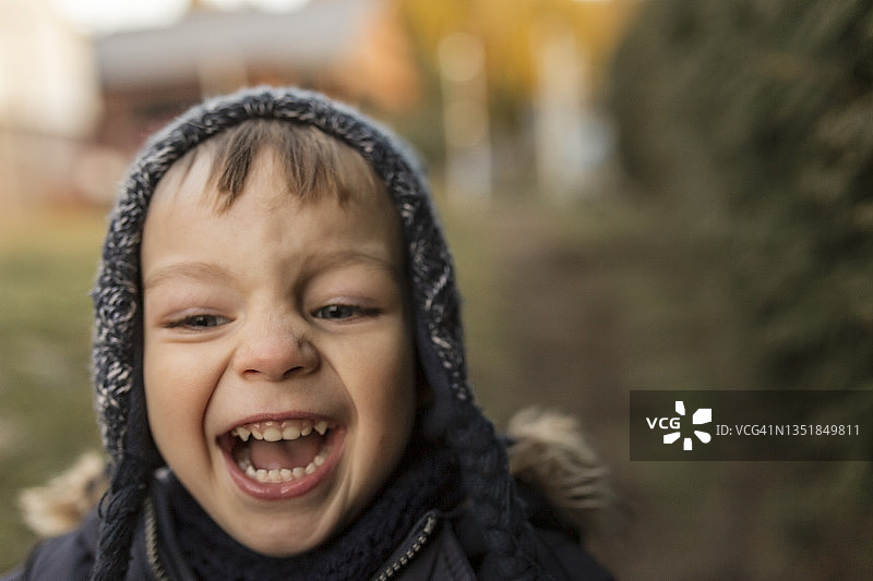 在后院穿着暖和衣服欢笑奔跑的幼儿男孩图片素材