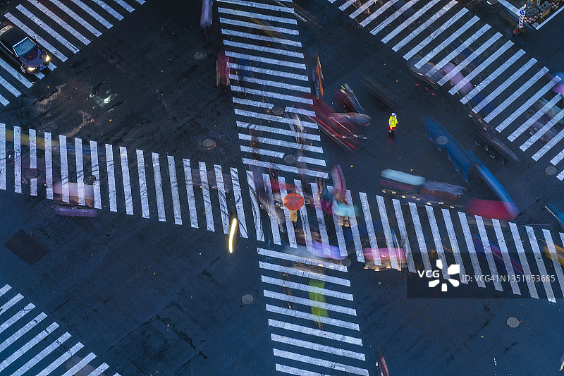 十字路口人群中撑着红色雨伞的亚洲女人图片素材