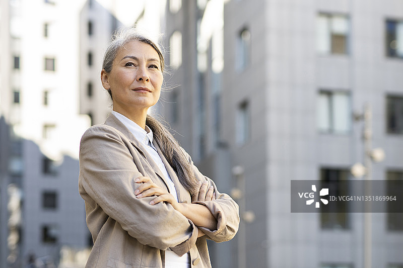 自信的中年妇女在城市中双手交叉站立图片素材
