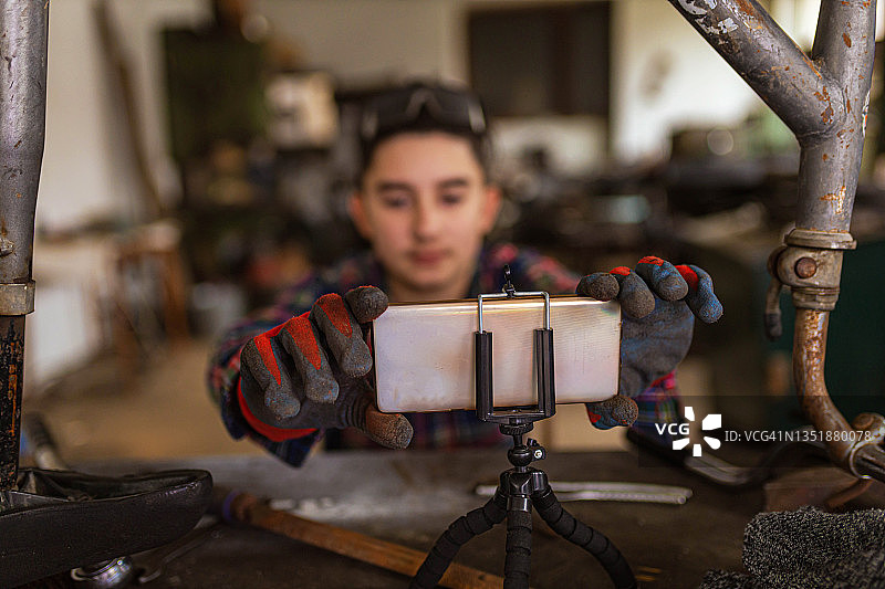青少年男孩在观看自行车修理DIY教程时调整手机图片素材