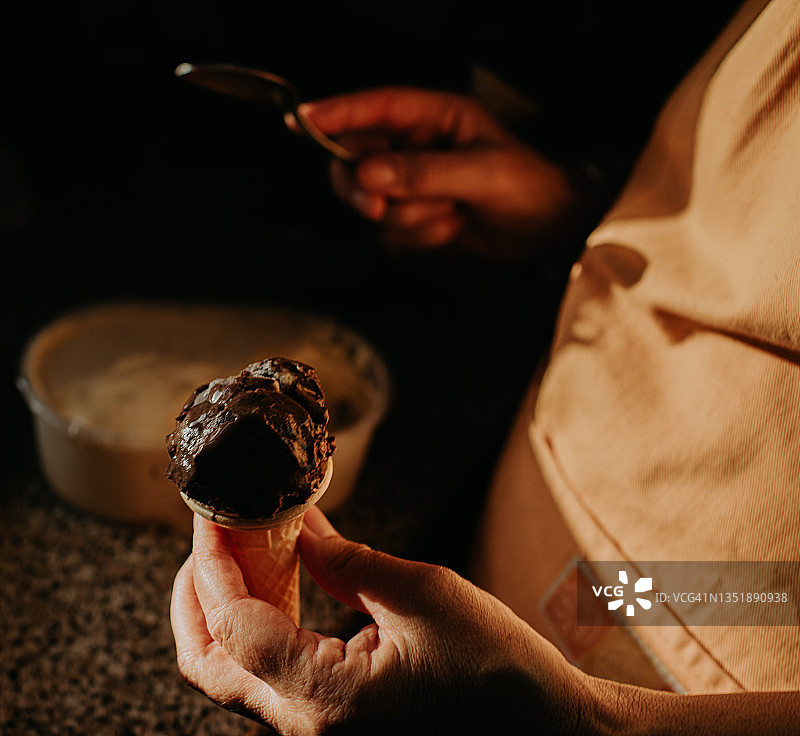 女人把巧克力冰淇淋放在小华夫饼筒里的特写图片素材