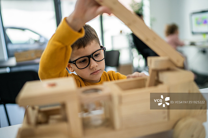 坐在客厅玩木制卡车的男孩图片素材