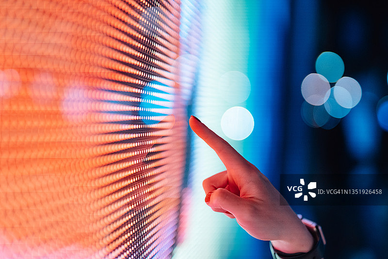 黑暗中，女性的手触摸发光数字显示屏的特写图片素材