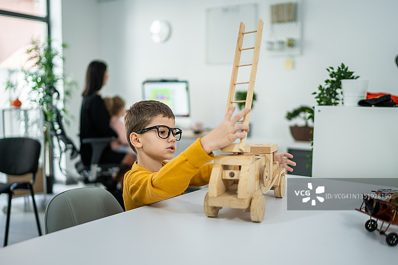 坐在客厅玩木制卡车的男孩图片素材