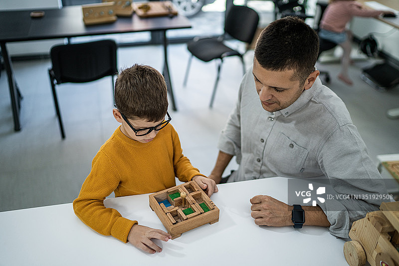 男老师和小男孩在日托中心玩棋盘游戏图片素材