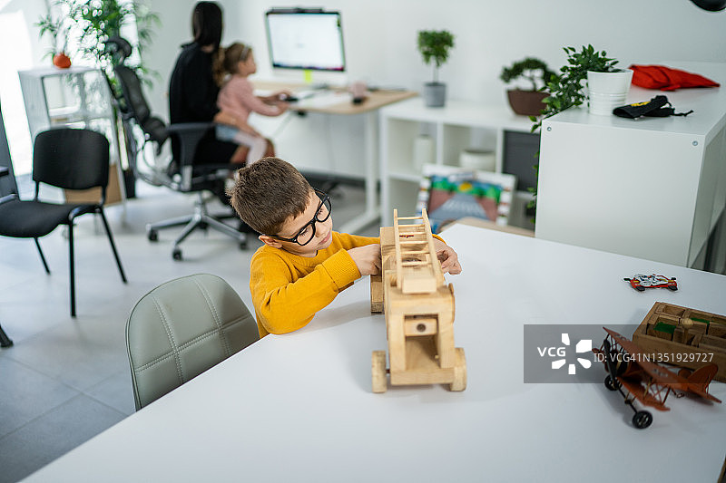 坐在客厅玩木制卡车的男孩图片素材