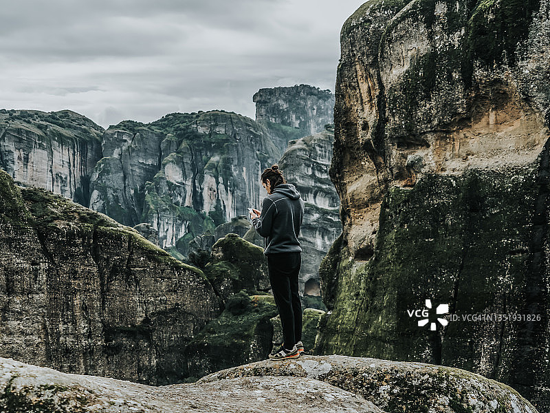 旅行者在岩石山顶用手机欣赏自然风光图片素材