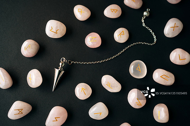 银色探测摆和玫瑰石英符文，黑色背景，魔法神秘仪式概念，扁平风格宏摄影图片素材