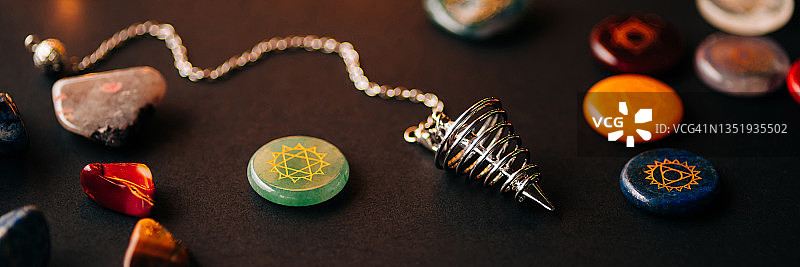 黄铜探测摆，半宝石与金色脉轮，黑色背景上的魔法概念花环图片素材