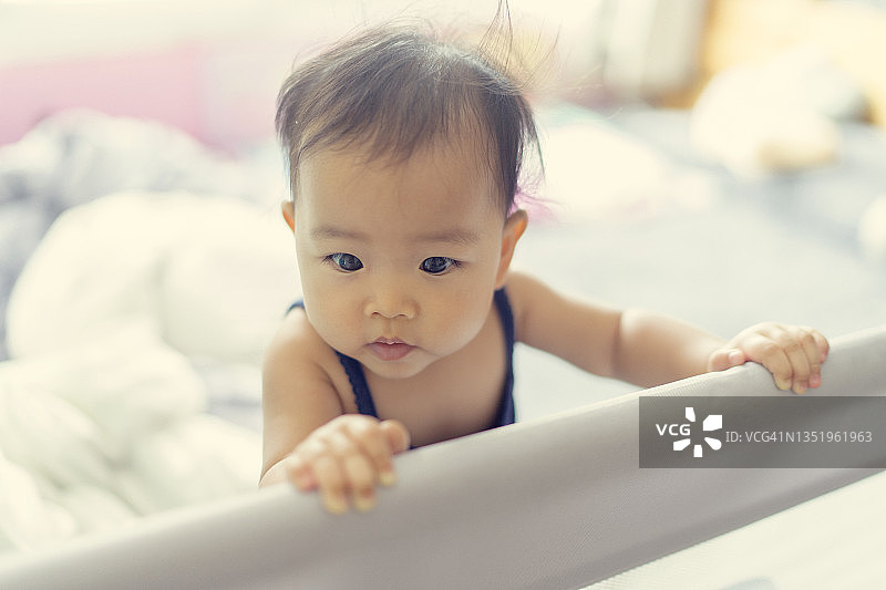 在婴儿围栏里哭喊的亚洲女婴（6-9个月大），表达消极情绪图片素材