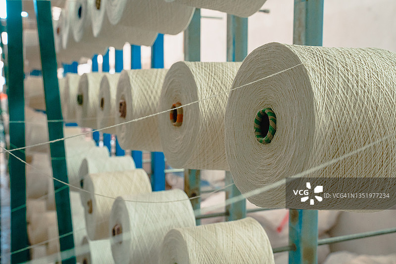 纺织厂工业整经针织横梁机上的白色纱线筒管线锥图片素材