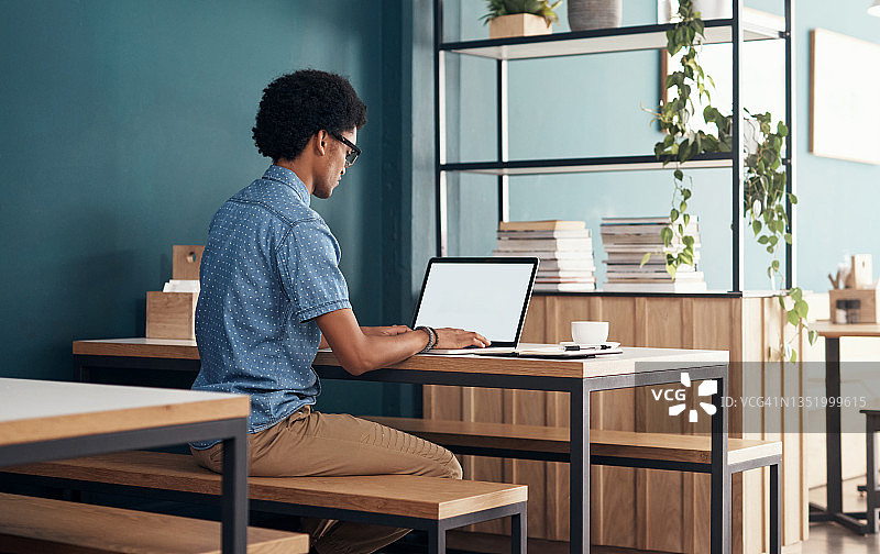 年轻男人独自在咖啡馆使用笔记本电脑进行远程工作图片素材