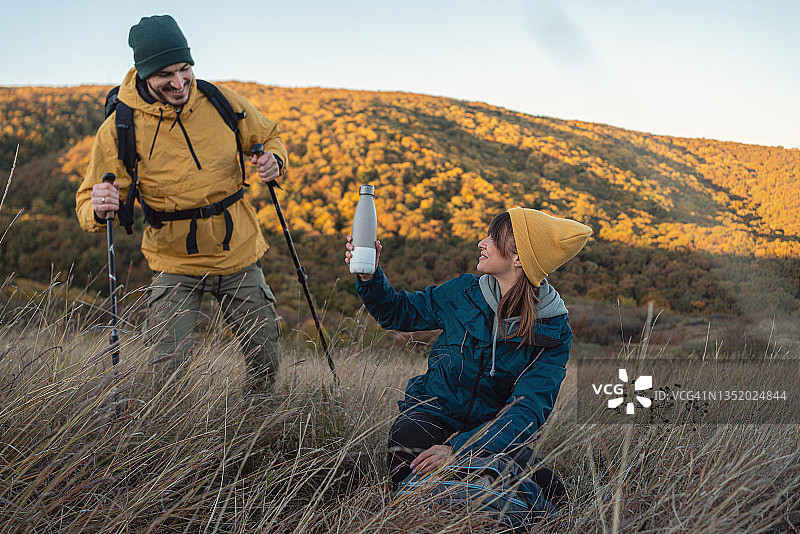 关怀的女人给男友提供保温瓶里的热饮，以便他在徒步旅行中恢复精神图片素材