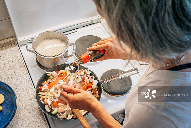 在亚洲风味晚餐中加入蚝油的女人图片素材