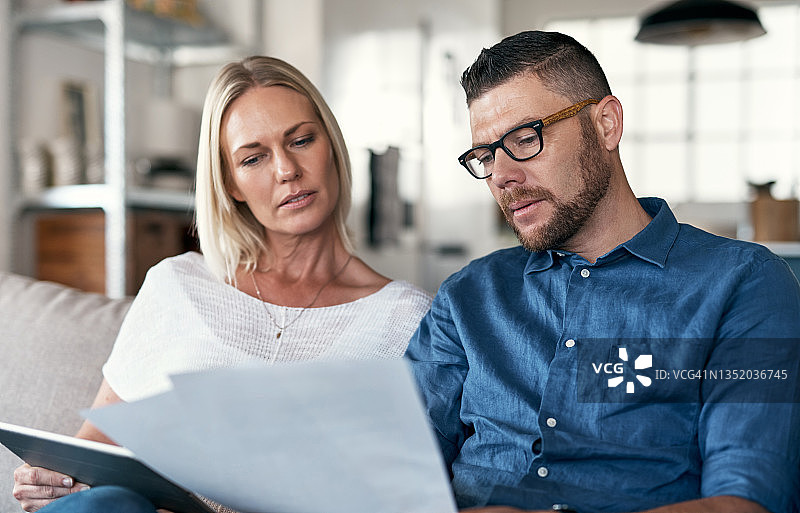 情侣坐在休息室里，使用平板电脑查看账单图片素材