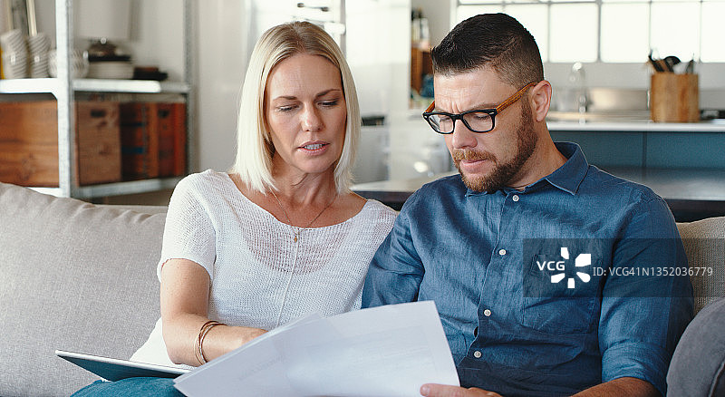 情侣坐在休息室里，使用平板电脑查看账单图片素材