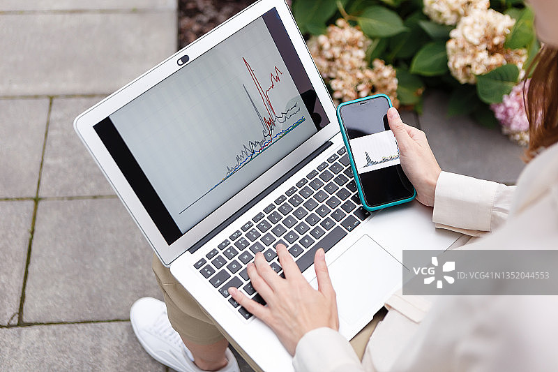 女人手持笔记本电脑和智能手机，观看比特币增长图表图片素材