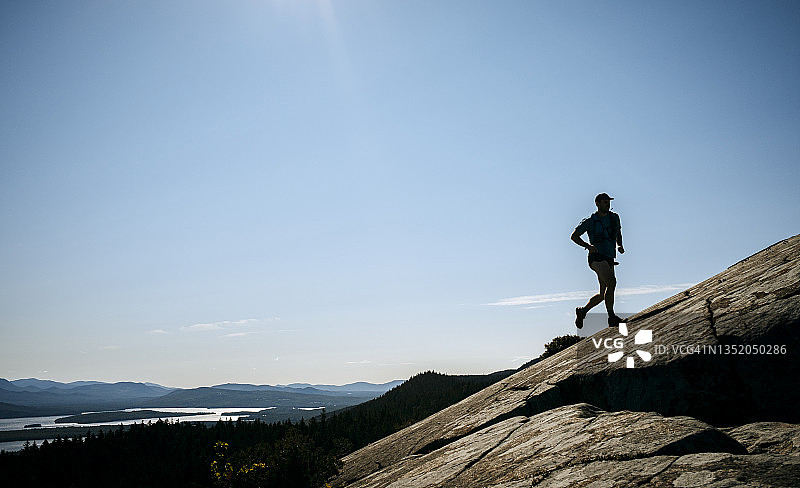 男子在缅因州格林维尔的岩石山顶附近跑步图片素材