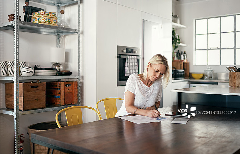 女人在厨房餐桌旁签署合同场景照片图片素材