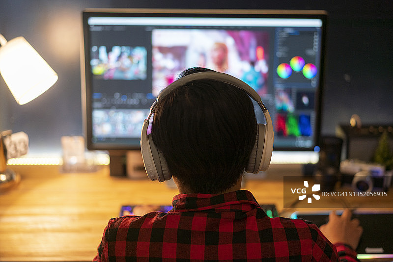 男人戴着耳机在电脑上进行视频编辑图片素材