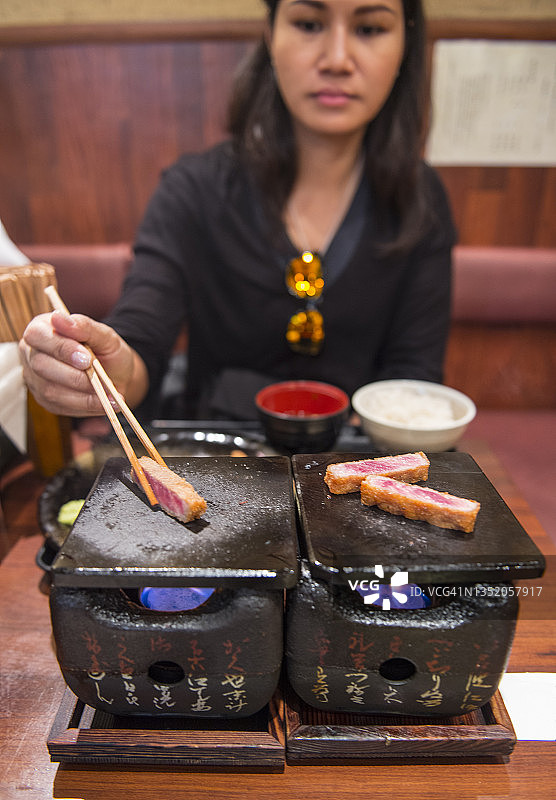 女人在传统日式炉子上烹饪炸牛排图片素材