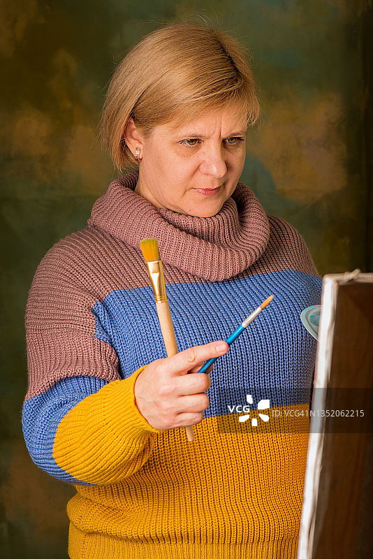 女艺术家用画笔绘画，画布在画架上图片素材