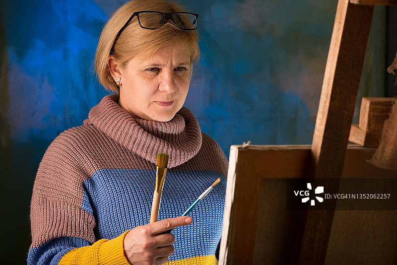 女艺术家用画笔绘画，画布在画架上图片素材