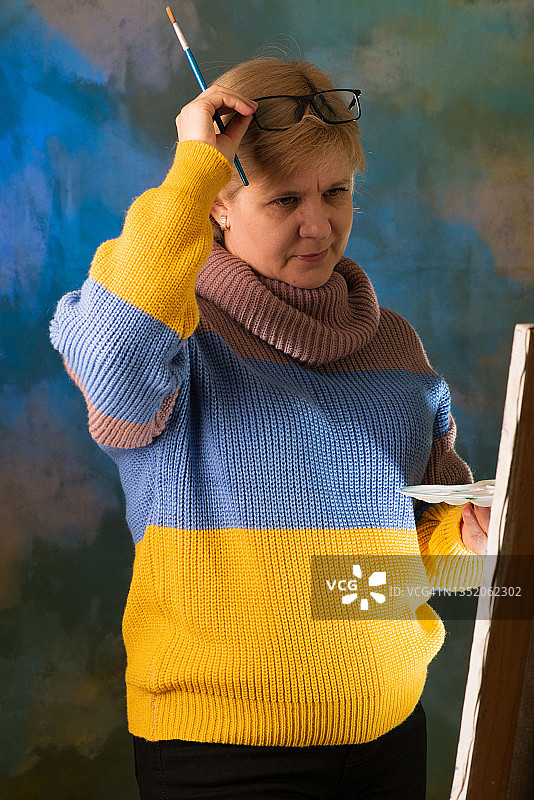 女艺术家用画笔绘画，画布在画架上图片素材