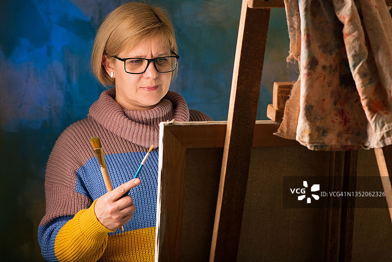 女艺术家用画笔绘画，画布在画架上图片素材