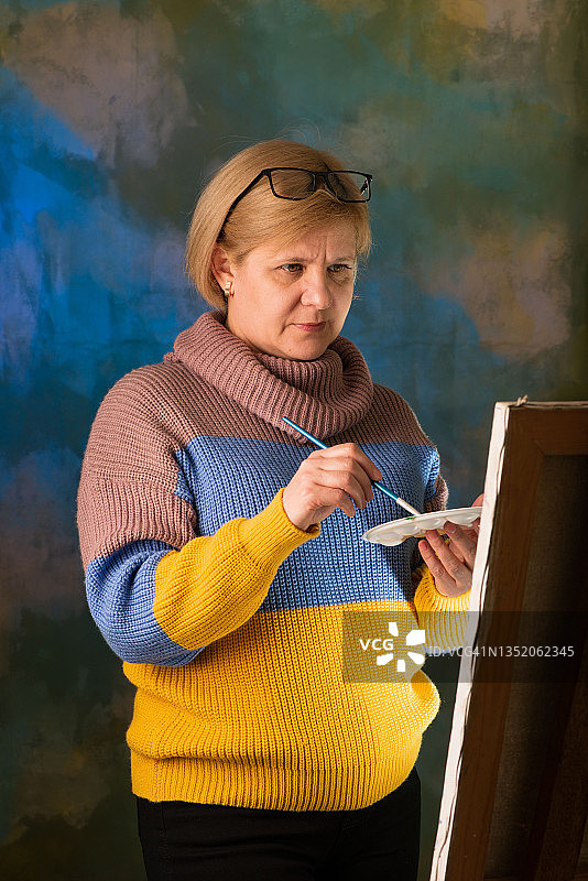 女艺术家用画笔绘画，画布在画架上图片素材