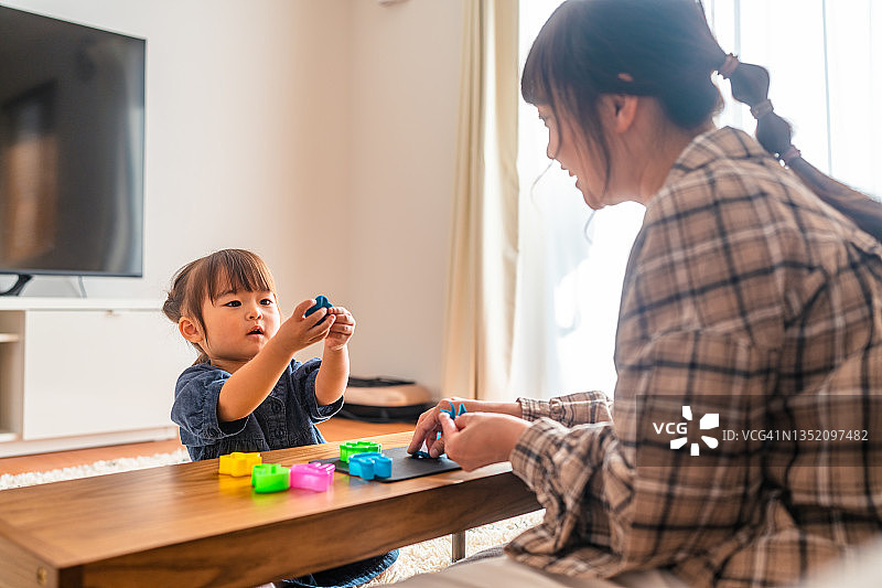 小女孩和妈妈在家里的客厅用彩色黏土捏造型图片素材