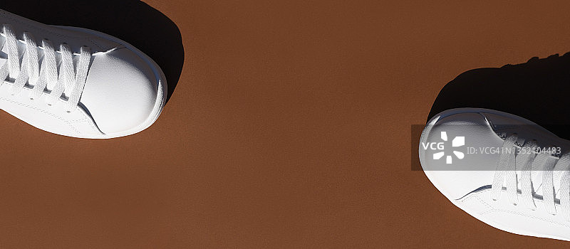 棕色背景上的白色时尚运动鞋图片素材