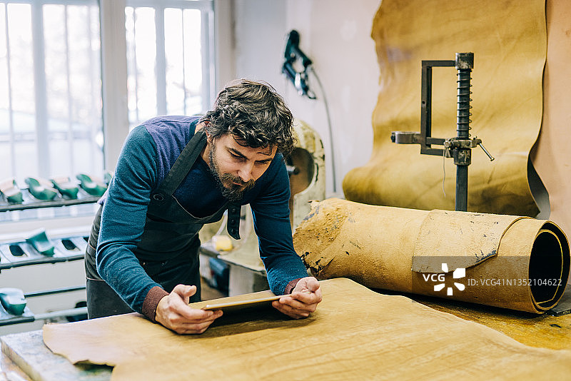 年轻的鞋匠在他的工作室里使用数位板图片素材