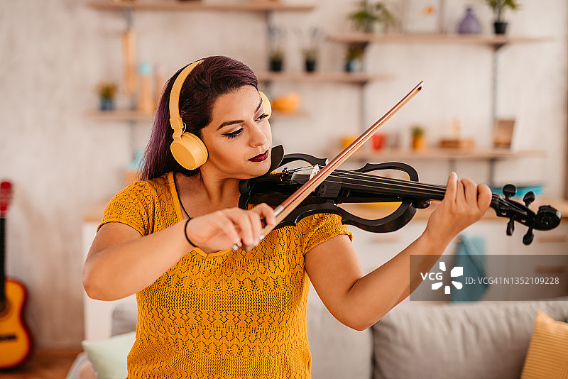 年轻的小提琴手在家练习演奏图片素材